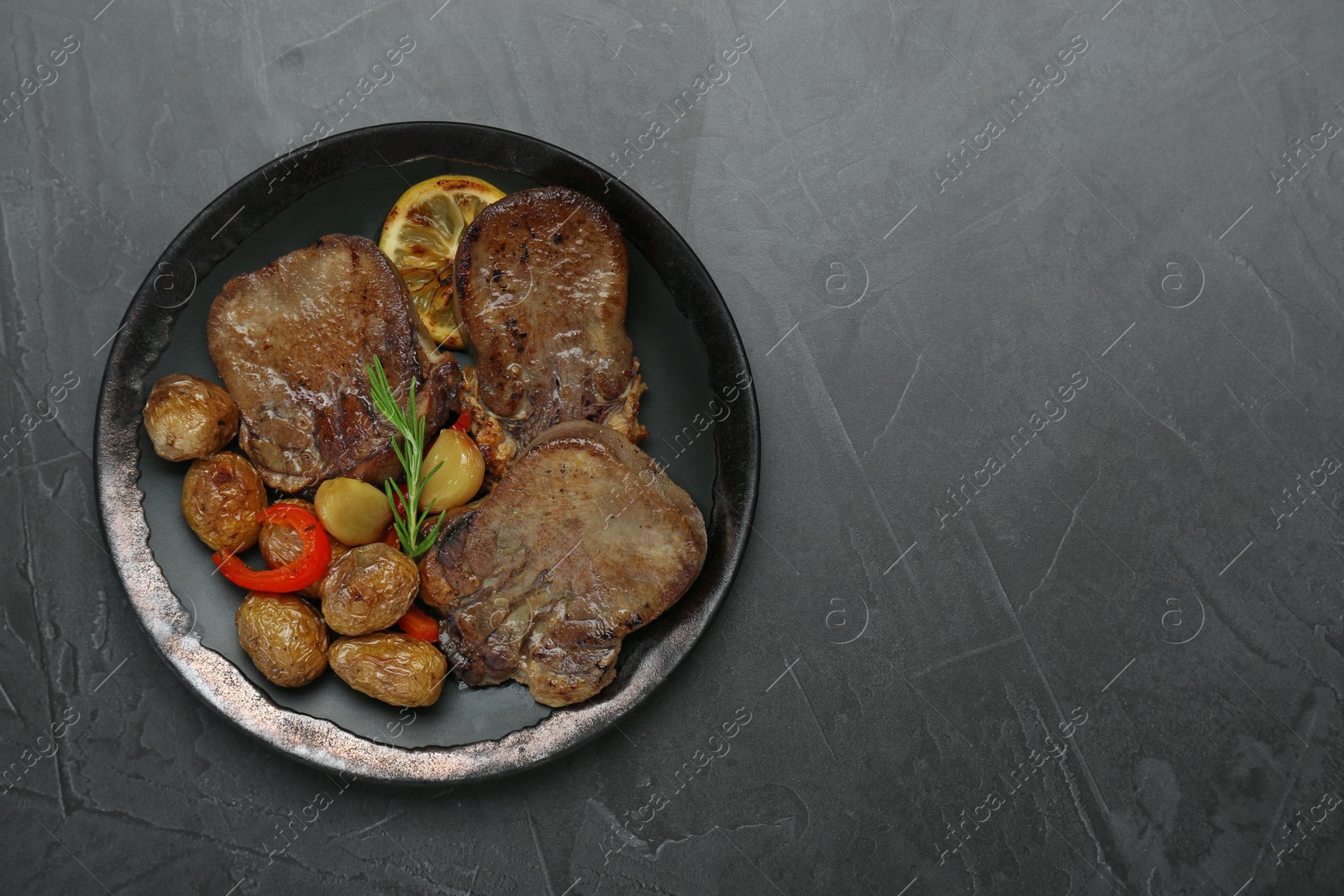 Photo of Tasty beef tongue pieces, rosemary, lemon and potatoes on grey table, top view. Space for text