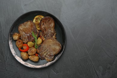 Photo of Tasty beef tongue pieces, rosemary, lemon and potatoes on grey table, top view. Space for text