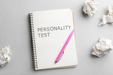 Image of Notebook with text Personality Test, pen and crumpled sheets of paper on light background, flat lay