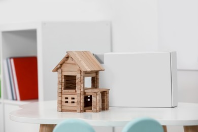Photo of Wooden house on white table indoors. Children's toy