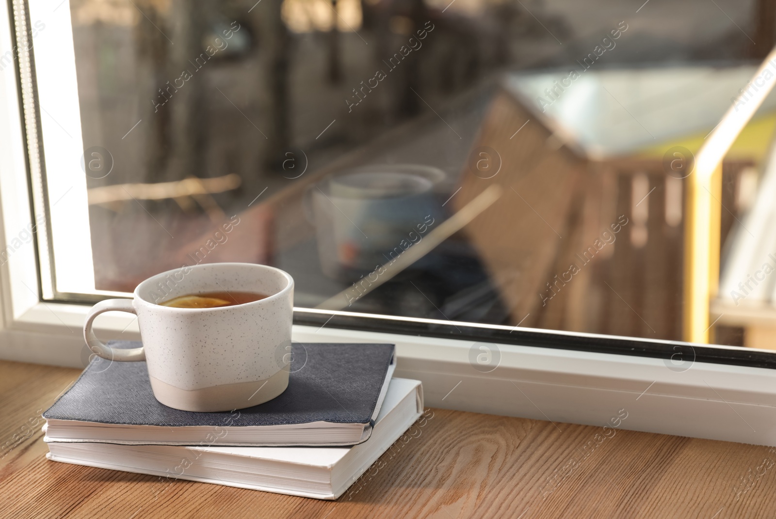 Photo of Cup of winter drink and books on windowsill. Space for text