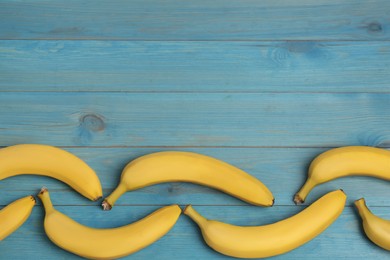 Ripe yellow bananas on light blue wooden table, flat lay. Space for text