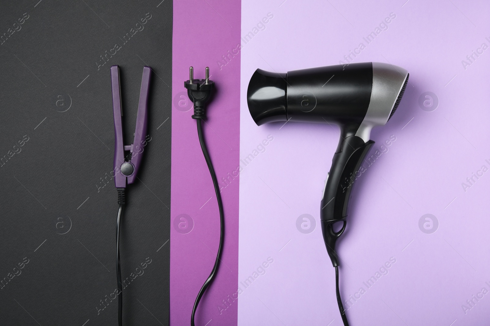 Photo of Hair dryer and iron on color background, flat lay. Professional hairdresser tools