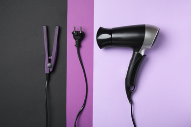 Hair dryer and iron on color background, flat lay. Professional hairdresser tools