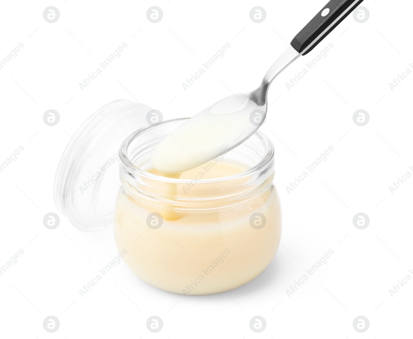 Photo of Condensed milk flowing down from spoon into jar isolated on white