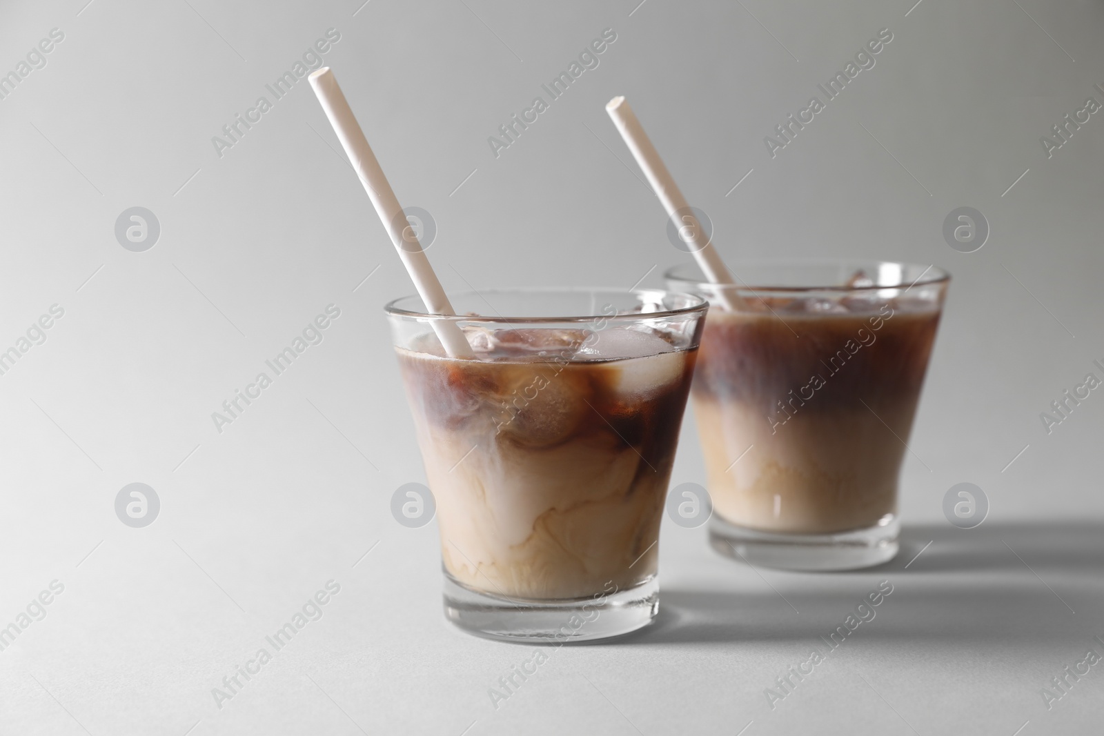 Photo of Refreshing iced coffee with milk in glasses on grey background. Space for text