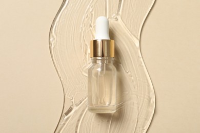 Bottle of cosmetic serum on beige background, top view