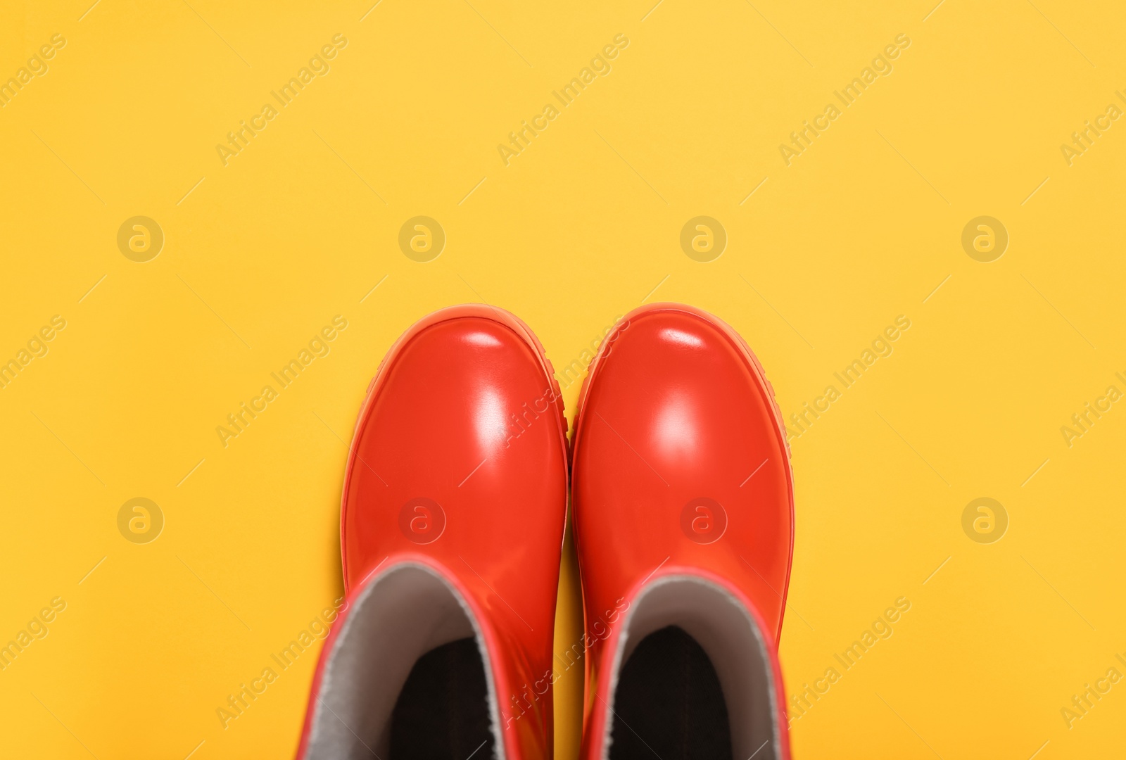 Photo of Red rubber boots on orange background, top view