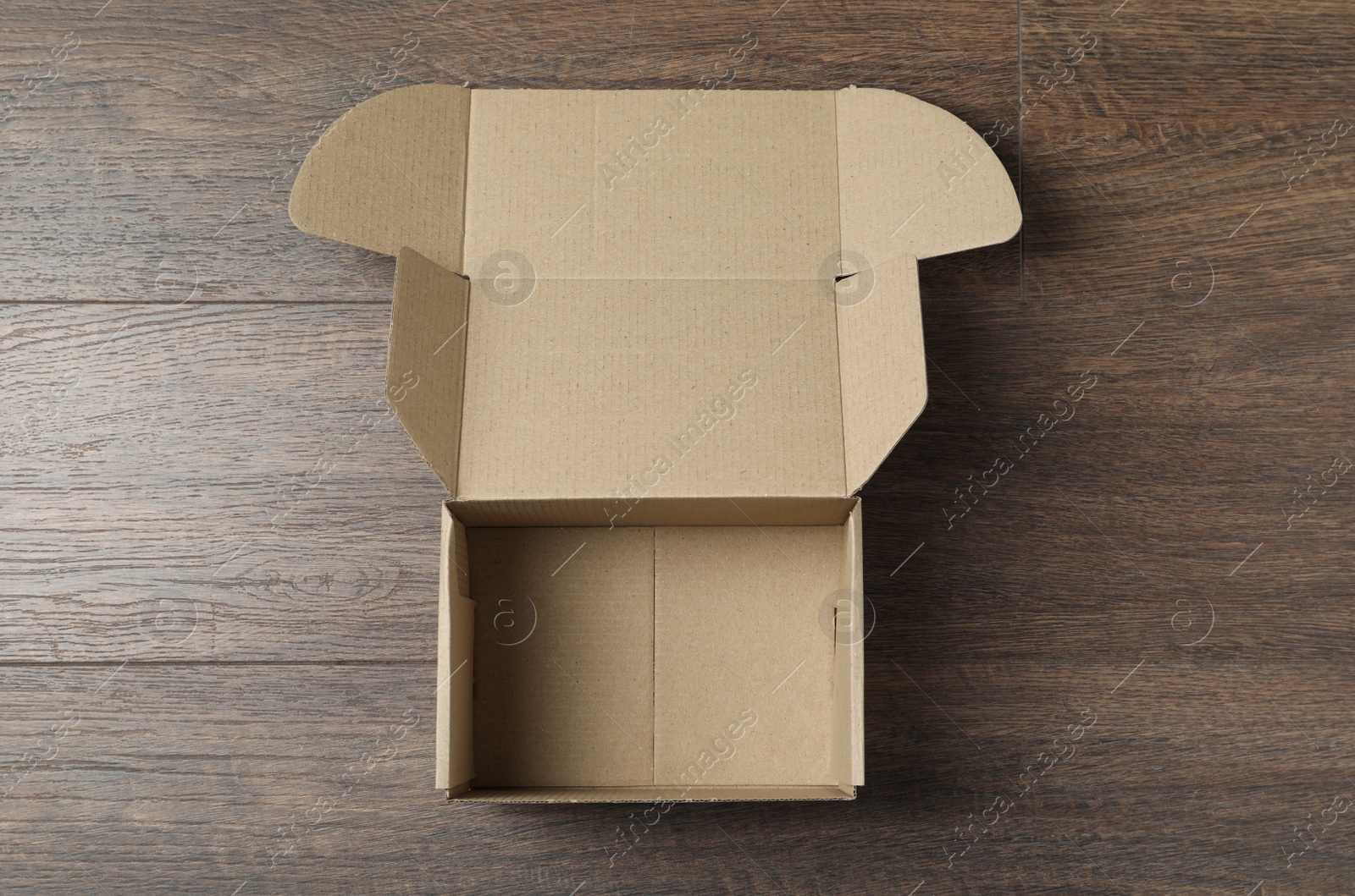 Photo of Empty open cardboard box on wooden table, top view