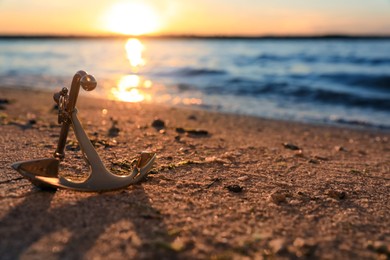 Photo of Metal anchor on shore near river at sunset