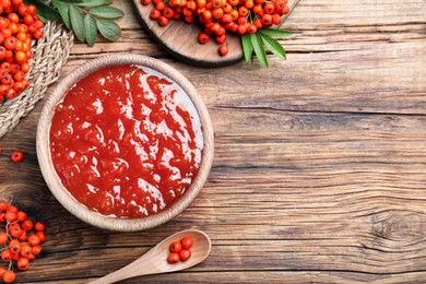 Photo of Flat lay composition with delicious rowan jam and berries on wooden table. Space for text