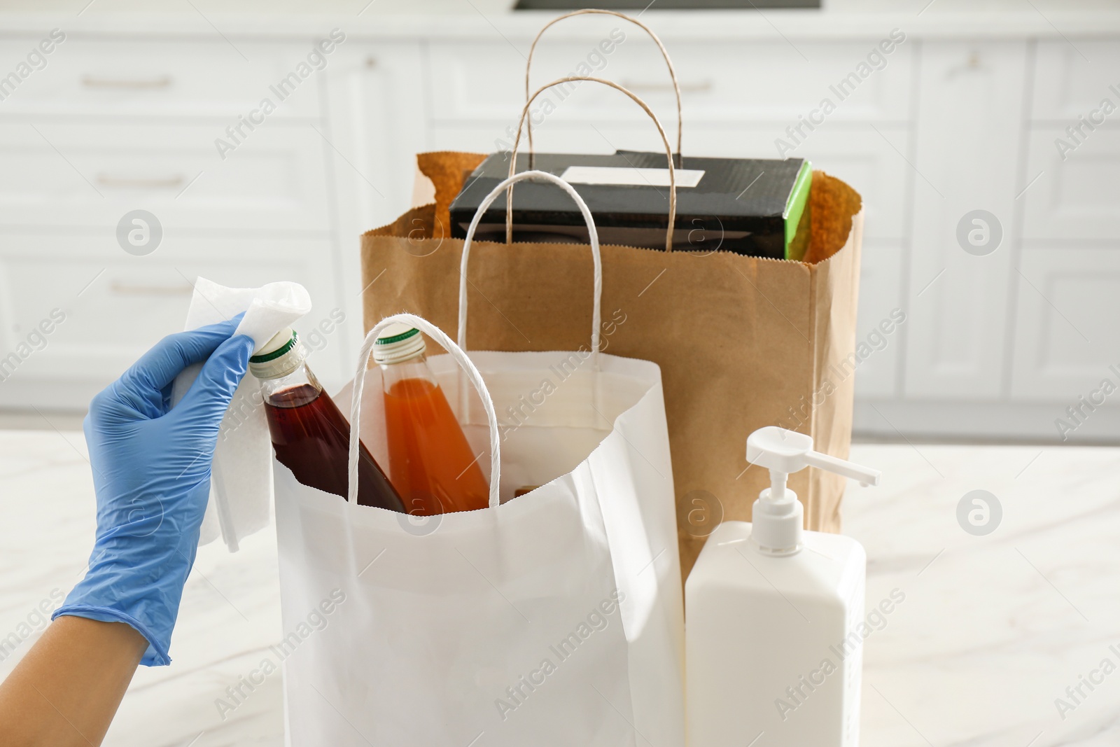 Photo of Woman cleaning newly purchased items with antiseptic wipe indoors, closeup. Preventive measures during COVID-19 pandemic