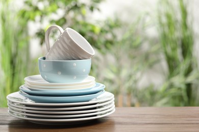 Photo of Beautiful ceramic dishware and cup on wooden table outdoors, space for text