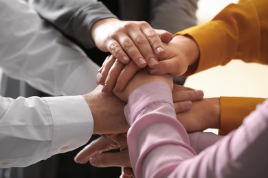 Photo of Young people putting their hands together on blurred background, closeup