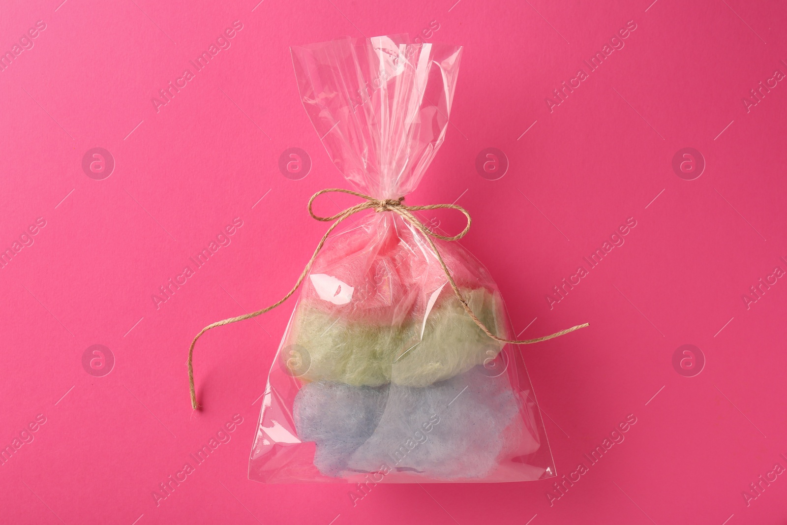 Photo of Packaged sweet cotton candy on pink background, top view