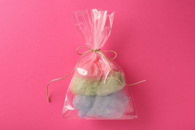 Photo of Packaged sweet cotton candy on pink background, top view