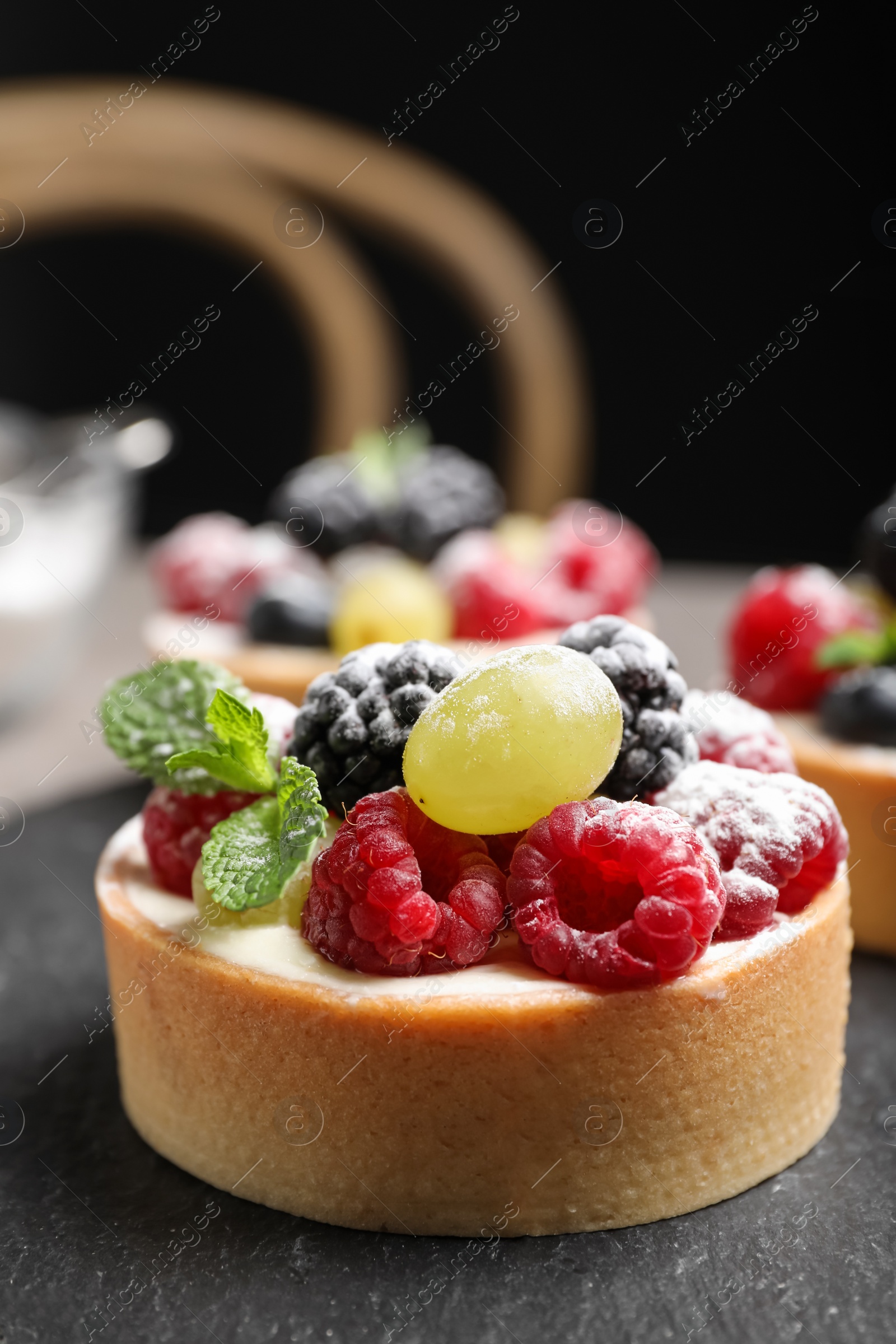 Photo of Delicious tartlet with berries on slate board, closeup
