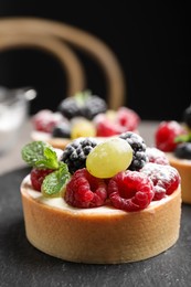 Delicious tartlet with berries on slate board, closeup