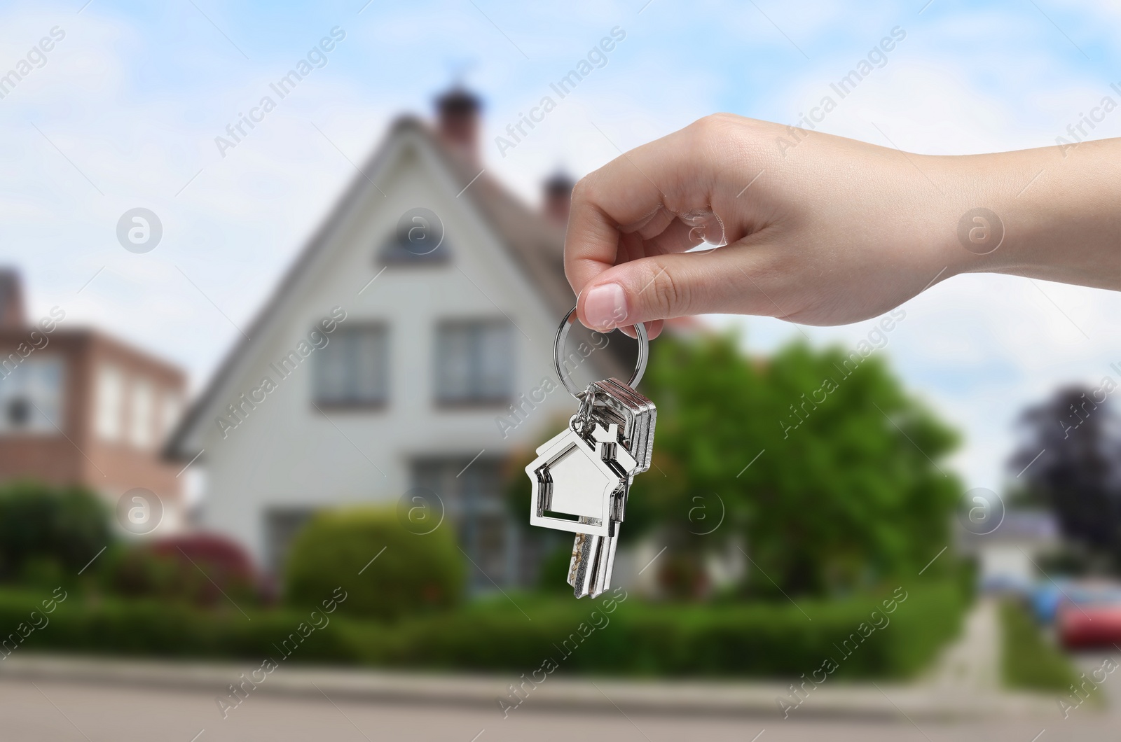 Image of Woman holding keys near house outdoors, closeup