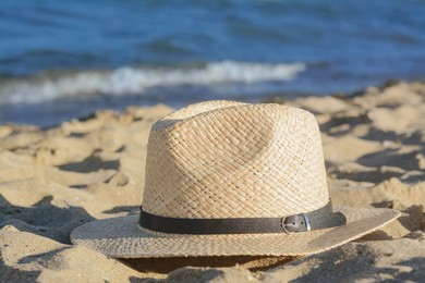 Photo of Stylish straw hat on sandy beach near sea