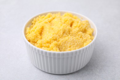 Photo of Tasty cornmeal in bowl on light gray table, closeup