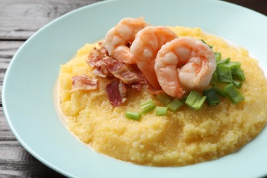 Plate with fresh tasty shrimps, bacon and grits on dark wooden table, closeup