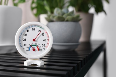 Photo of Round mechanical hygrometer on black table indoors. Space for text