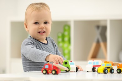 Photo of Children toys. Cute little boy playing with toy cars at white table in room, space for text