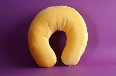 Photo of One yellow travel pillow on violet background