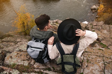 Photo of Couple of travelers with backpacks enjoying beautiful view near mountain river. Autumn vacation