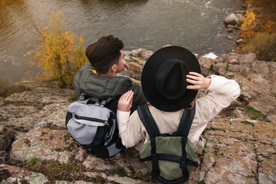 Couple of travelers with backpacks enjoying beautiful view near mountain river. Autumn vacation