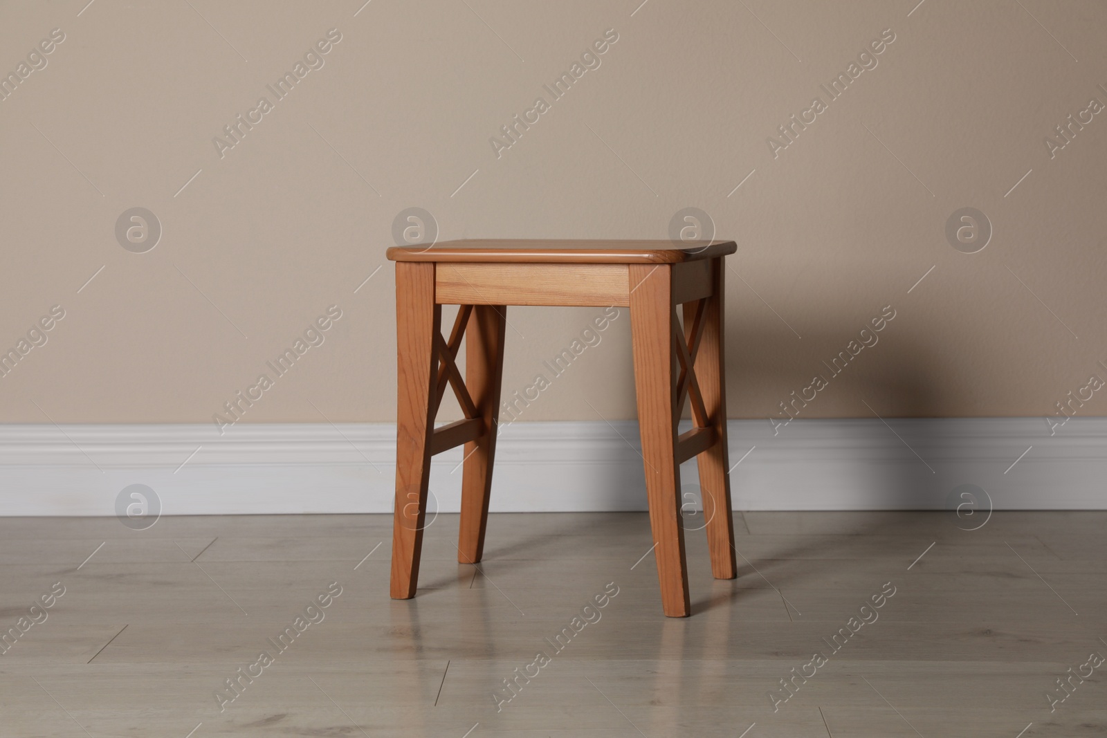 Photo of Stylish wooden stool near beige wall indoors