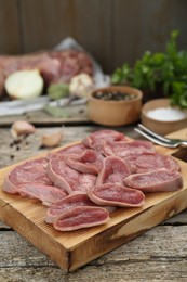 Photo of Board with slices of raw beef tongue and products on wooden table, closeup