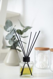 Photo of Aromatic reed air freshener on white countertop in bathroom