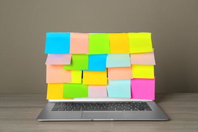 Photo of Laptop with colorful sticky notes on wooden table