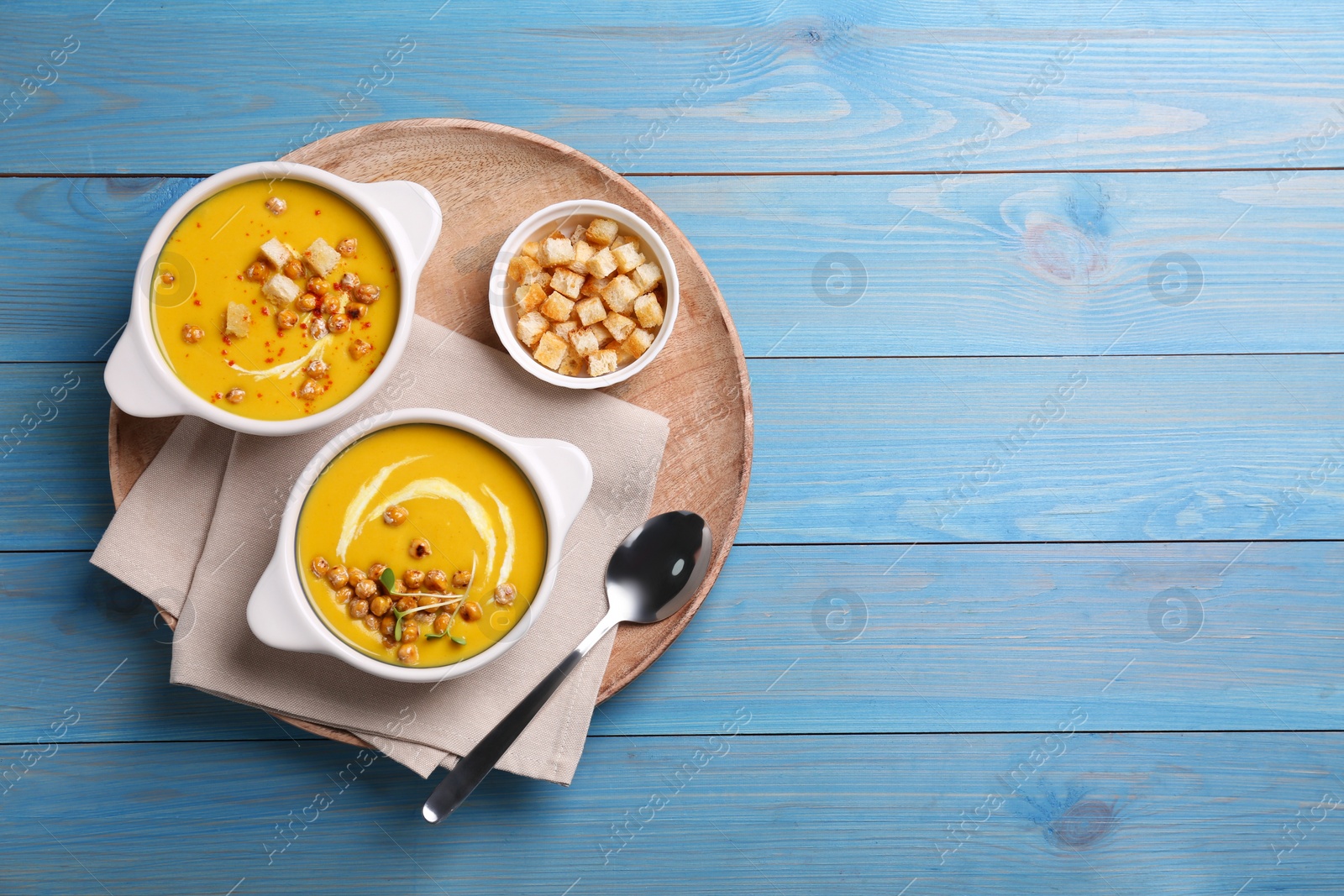 Photo of Delicious cream soup with chickpeas on light blue wooden table, top view. Space for text