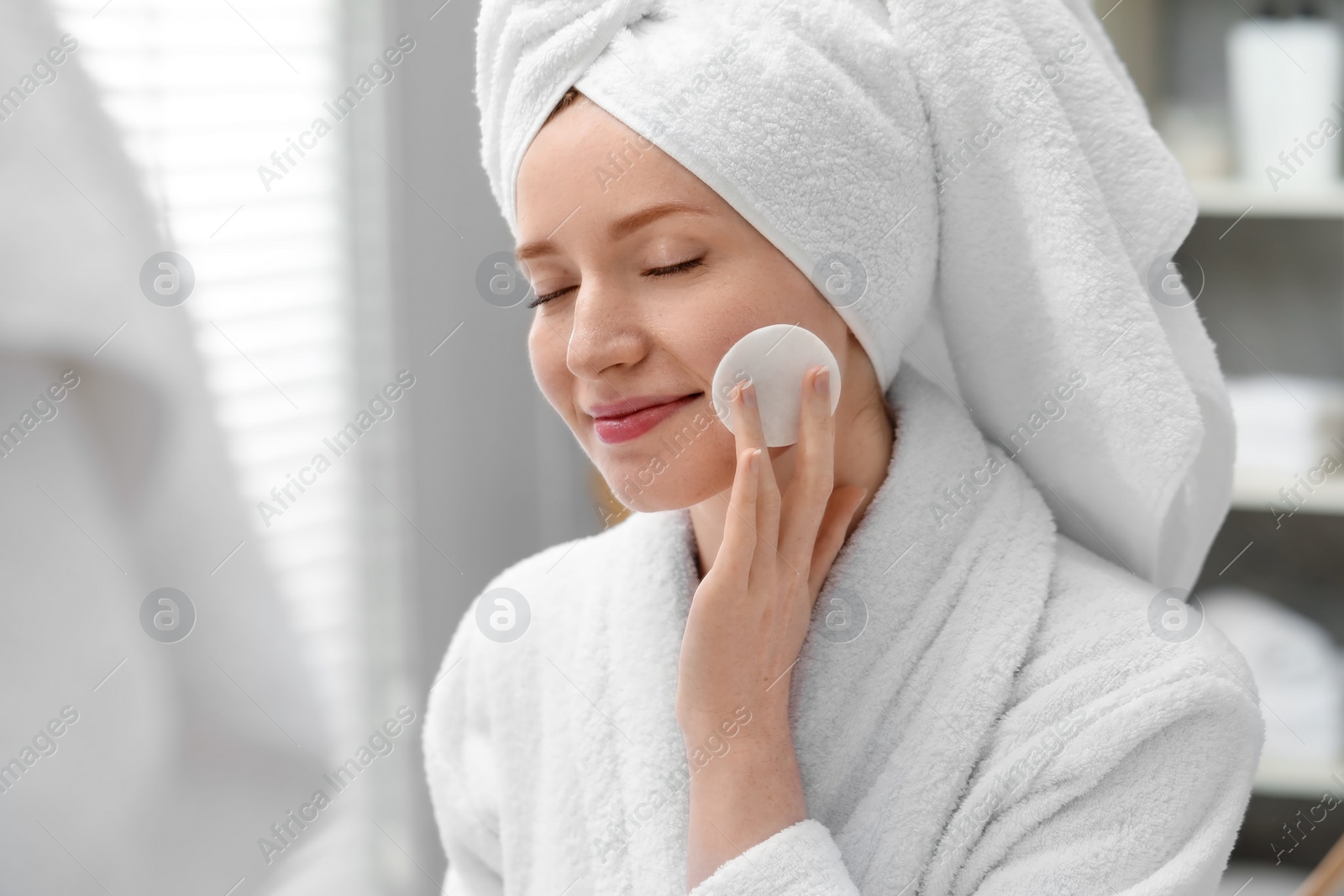 Photo of Beautiful woman with freckles wiping face in bathroom