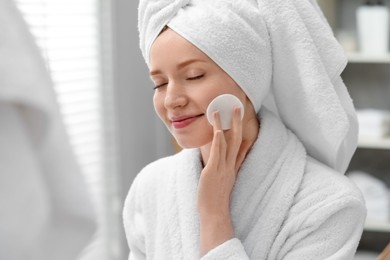 Photo of Beautiful woman with freckles wiping face in bathroom