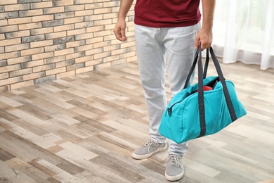 Photo of Young man with sports bag in room