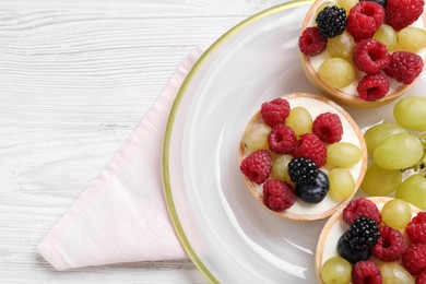 Delicious tartlets with berries on white wooden table, top view
