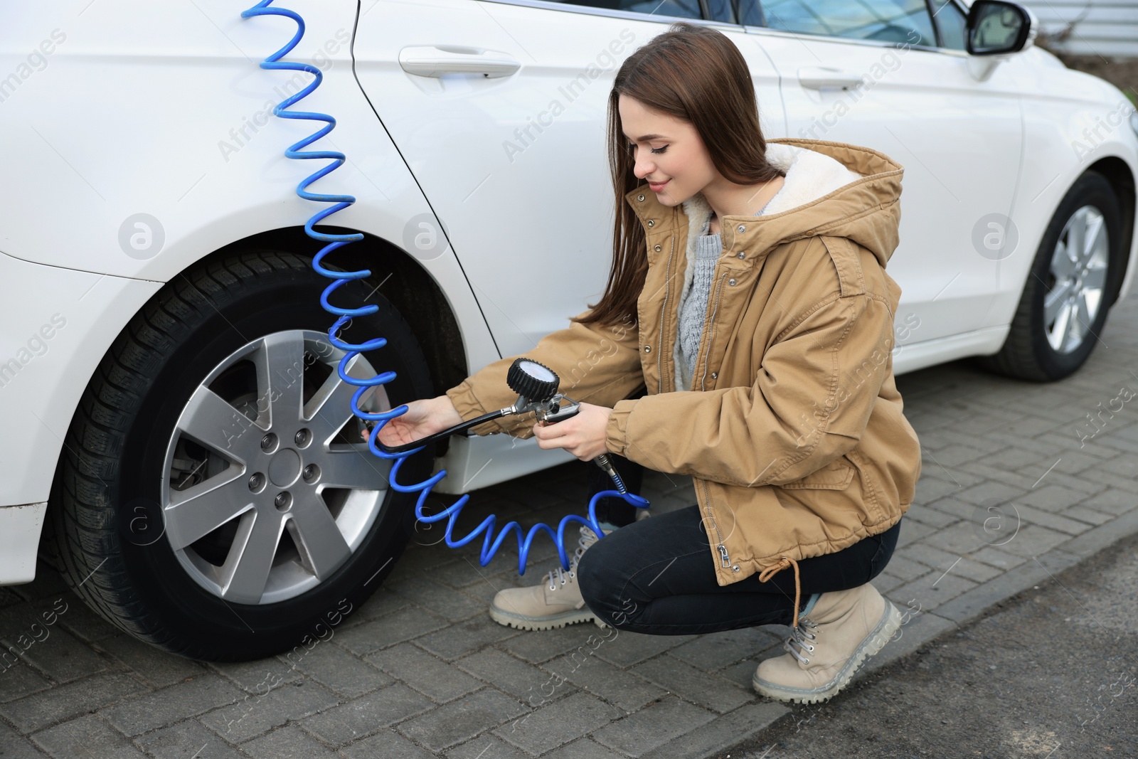 Photo of Young woman inflating tire at car service