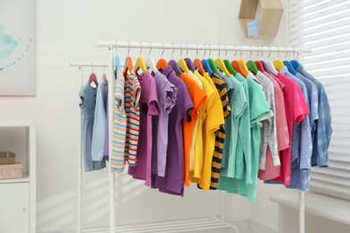 Photo of Different child's clothes hanging on racks indoors