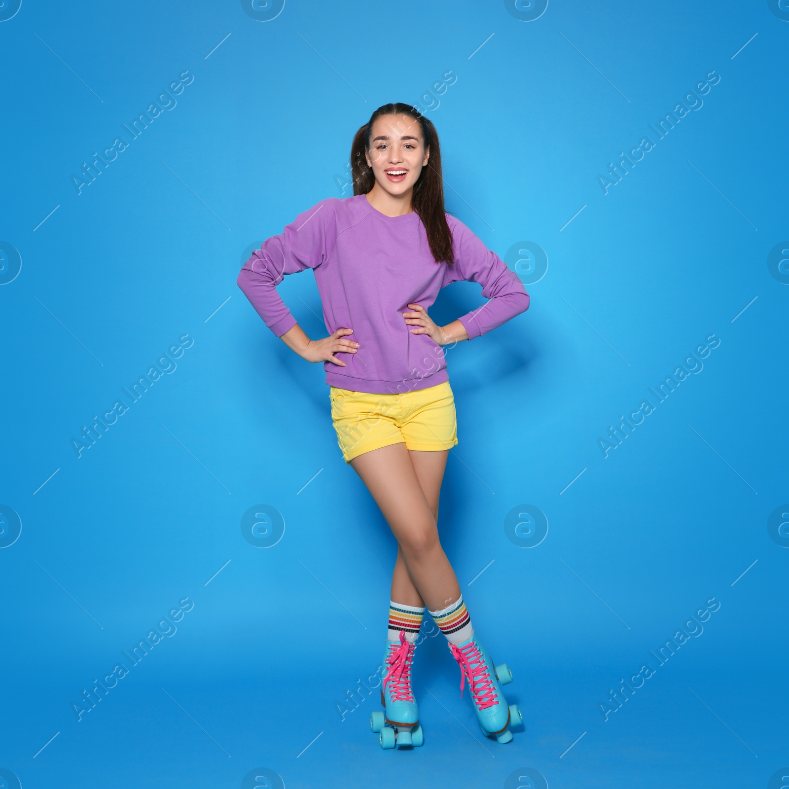 Photo of Full length portrait of young woman with roller skates on color background