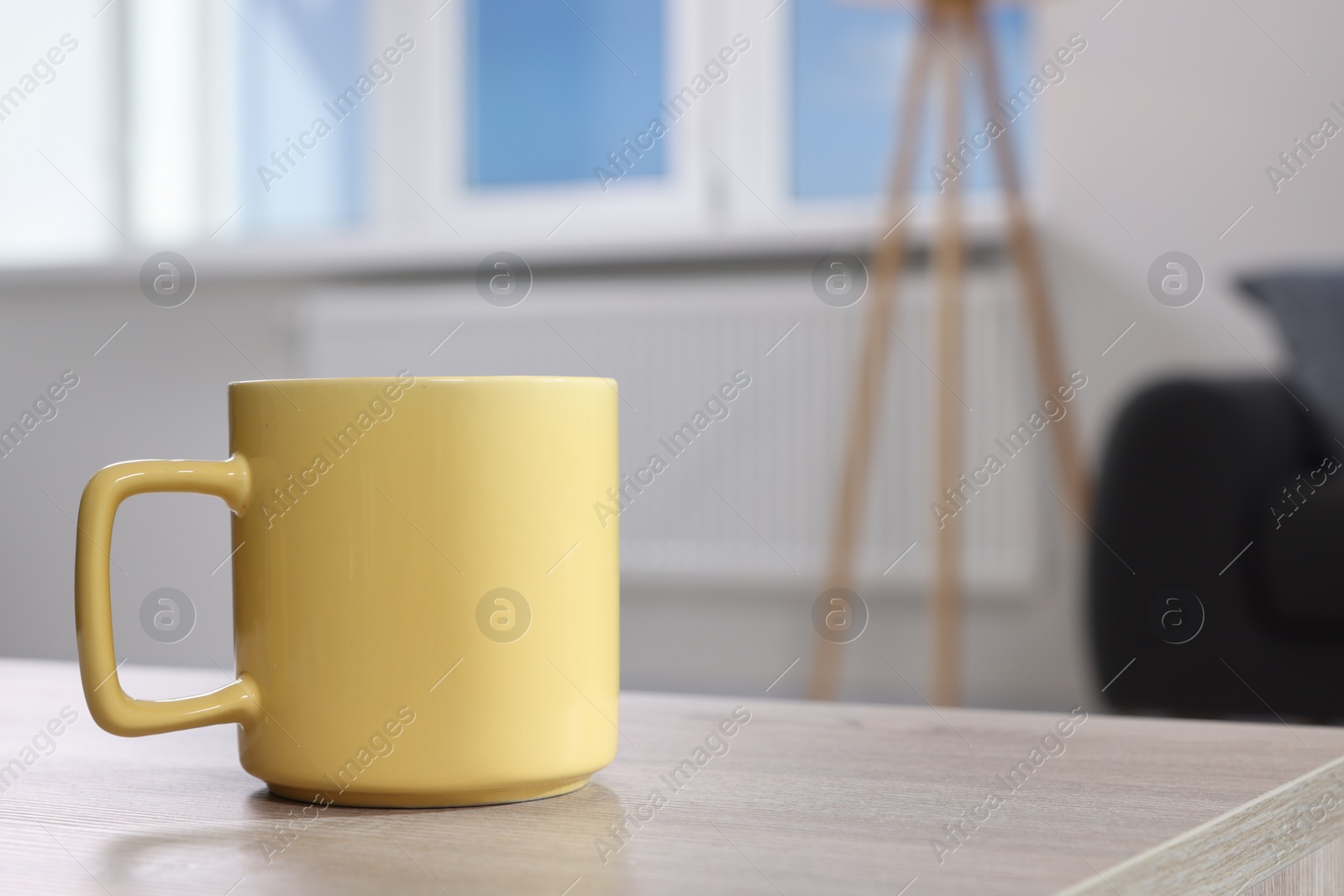 Photo of Yellow mug on wooden table indoors, space for text