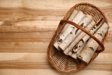 Wicker basket with firewood on floor indoors, top view. Space for text