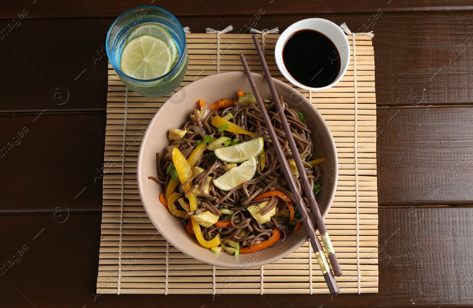 Photo of Stir-fry. Delicious cooked noodles with chicken and vegetables in bowl served on wooden table, flat lay