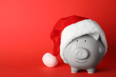 Photo of Cute piggy bank with Santa hat on color background