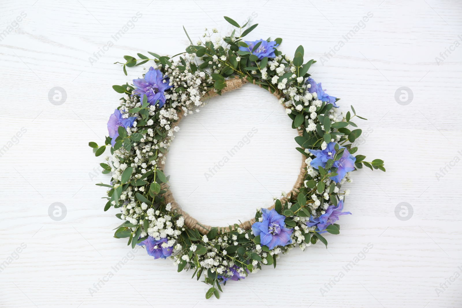 Photo of Beautiful flower wreath on white wooden background, top view