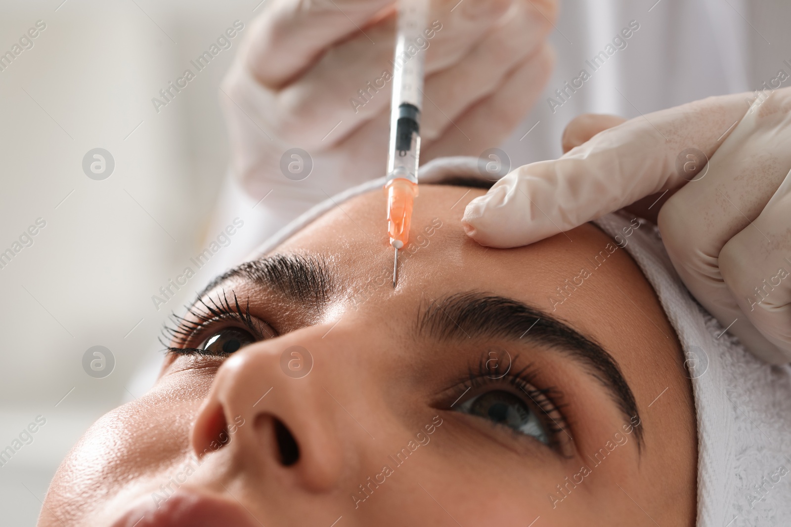 Photo of Doctor giving facial injection to young woman in clinic, closeup. Cosmetic surgery