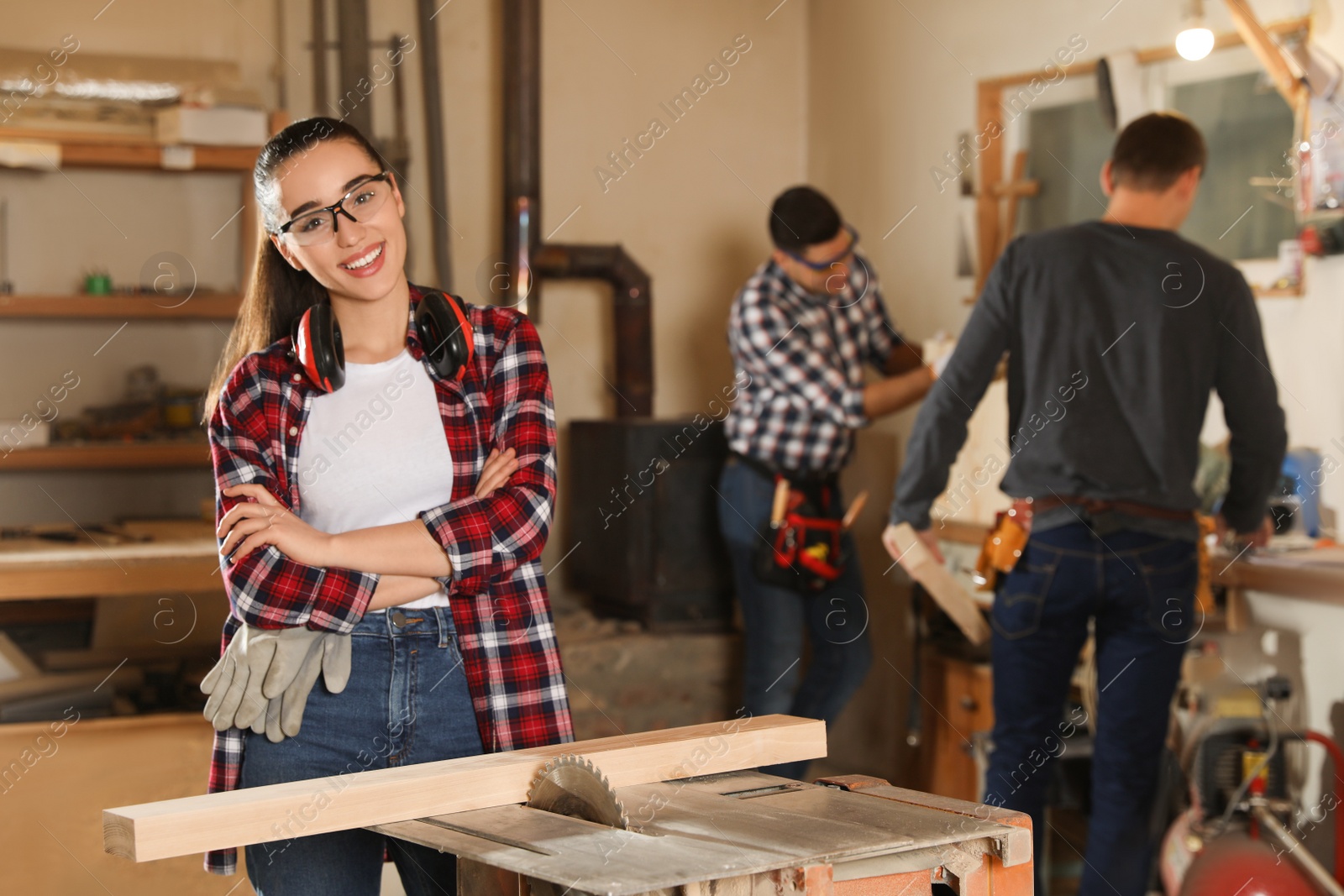 Photo of Professional carpenter near sawmill machine and colleagues in workshop